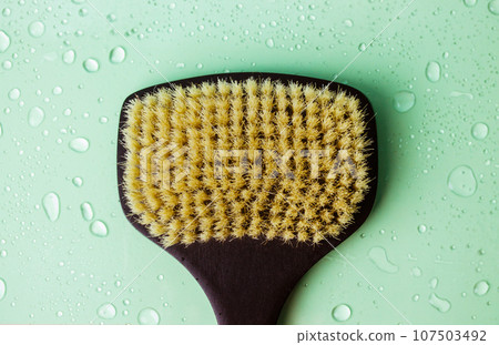 Black brush for dry massage with cactus fibers stiff pile. Water drops on green. 107503492