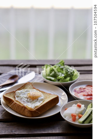 Breakfast of fried egg on toast, yogurt and vegetables 107504594