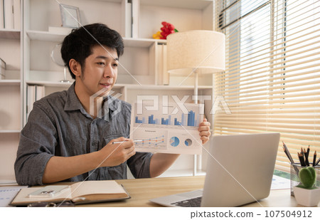 Man Working from Home, Video call with customers on laptop, Remote Business Communication, Telecommuting Professional, Virtual Video Call with Office Customer, Work from Home Concept. Man Working from Home, Video call with customers on laptop, Remote Business Communication, Telecommuting Professional, Virtual Video Call with Office Customer, Work from Home Concept. 107504912