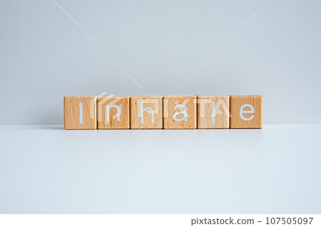Wooden blocks form the text "Inhale" against a white background. Wooden blocks form the text "Inhale" against a white background. 107505097
