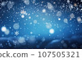 Serene winter scene with gentle snowflakes and ethereal bokeh against a deep blue sky. 107505321