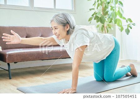 Senior woman doing yoga in the living room 107505451