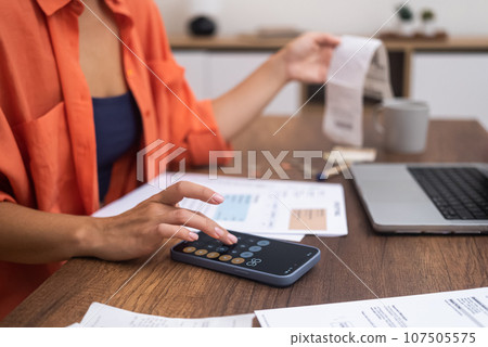 Smartphone Finance: With a laptop on the desk, a woman skillfully calculates household expenditures on her smartphone. Smartphone Finance: With a laptop on the desk, a woman skillfully calculates household expenditures on her smartphone. 107505575