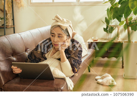Senior woman touching a tablet in the room Senior woman touching a tablet in the room 107506390