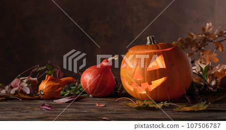 Halloween pumpkin head jack lantern with dried-up leaves. 107506787