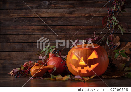 Halloween pumpkin head jack lantern with dried-up leaves. Halloween pumpkin head jack lantern with dried-up leaves. 107506798