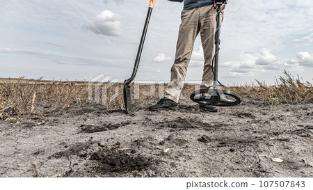 Archaeological and treasure hunting with a metal detector.Hunting for relics in the ground.Search for antiques.Soil research on gold nuggets.A man with a metal detector and a shovel.Finding research Archaeological and treasure hunting with a metal detector.Hunting for relics in the ground.Search for antiques.Soil research on gold nuggets.A man with a metal detector and a shovel.Finding research 107507843