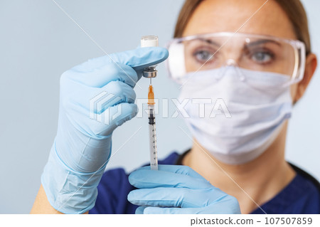 Doctor fills syringe with medicine from vial. Vaccination and immunization 107507859