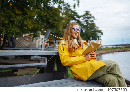 Young woman reading a book in the park. Relaxation, enjoying, solitude with nature. Young woman reading a book in the park. Relaxation, enjoying, solitude with nature. 107507863