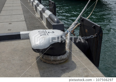 Tied rope on the knot around the mooring bollard. Nautical theme background 107508297