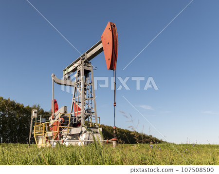 Operating oil and gas well in oil field, profiled against the blue sky Operating oil and gas well in oil field, profiled against the blue sky 107508500