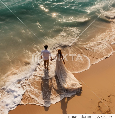 Breathtaking aerial view of the couple holding hands on a beach Breathtaking aerial view of the couple holding hands on a beach 107509026