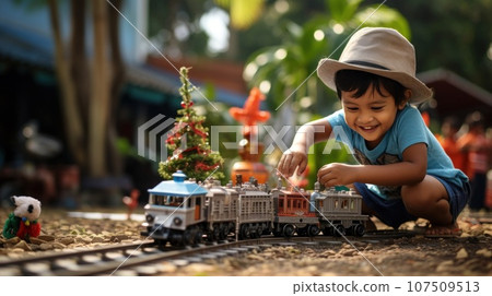 child plays with toy train sitteng ubder christma tree 107509513