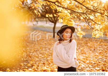 Sunny lifestyle portrait of young stylish woman walking on park, wearing cute trendy hat. Fashion concept. 107510362
