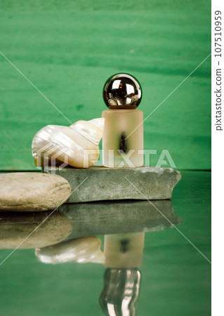 Makeup product, pearl seashell on emerald green background. Stylish beauty blog Moisturizing serum. Face body skin care. Essential cuticle oil flacon, perfume bottle. Luxury cosmetic on stone podium. 107510959