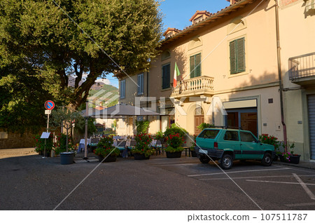 A cozy street with a restaurant with outdoor terrace or patio, tables served. Italy. Tuscany Region A cozy street with a restaurant with outdoor terrace or patio, tables served. Italy. Tuscany Region 107511787