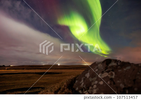 Aurora borealis above snowy mountain in winter landscape. Northern lights in Iceland creating beautiful natural phenomenon under night sky glowing. Polar scenery with magical reflection. Aurora borealis above snowy mountain in winter landscape. Northern lights in Iceland creating beautiful natural phenomenon under night sky glowing. Polar scenery with magical reflection. 107513457