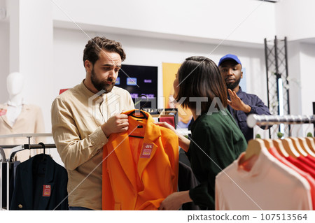 Mall security guard calming down two customers fighting over clothing item during sales. People shoppers arguing in clothing store, going crazy on Black Friday, hunting for bargains Mall security guard calming down two customers fighting over clothing item during sales. People shoppers arguing in clothing store, going crazy on Black Friday, hunting for bargains 107513564