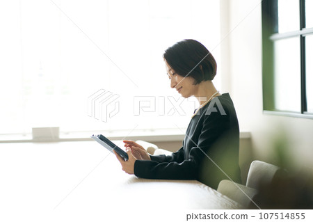 A woman in mourning clothes looking at a tablet 107514855