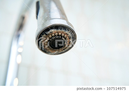 The chrome faucet is covered with lime scale. 107514975
