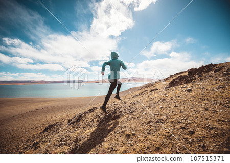 Woman trail runner cross country running at lakeside Woman trail runner cross country running at lakeside 107515371