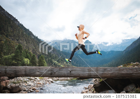 Woman trail runner cross country running in high altitude mountains 107515381
