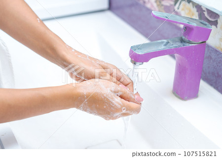woman washes her hands under running water from a tap in the bathroom, concept of hygiene and protection from bacteria woman washes her hands under running water from a tap in the bathroom, concept of hygiene and protection from bacteria 107515821