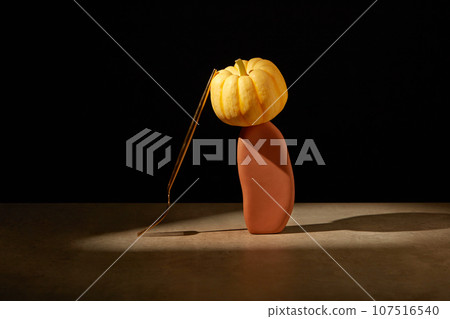 A pumpkin placed on an orange stone with a fork leaning on. Black background. Thanksgiving Day is a traditional day for family and friends to gather together for a special meal A pumpkin placed on an orange stone with a fork leaning on. Black background. Thanksgiving Day is a traditional day for family and friends to gather together for a special meal 107516540