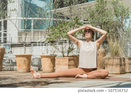 A woman doing yoga, pilates, and stretching on the rooftop A woman doing yoga, pilates, and stretching on the rooftop 107516732