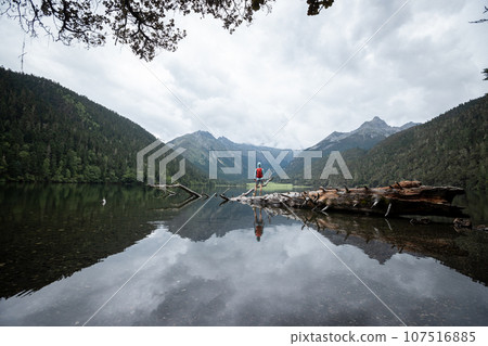 Hiking woman on a one plank bridge in high altitude mountains Hiking woman on a one plank bridge in high altitude mountains 107516885