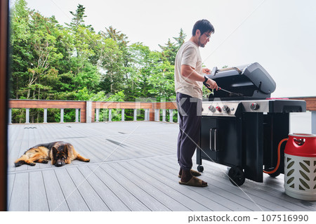 A man cooks on a grill on the veranda. 107516990