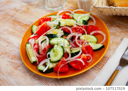 Delicious summer salad of cucumbers and tomatoes on plate Delicious summer salad of cucumbers and tomatoes on plate 107517029