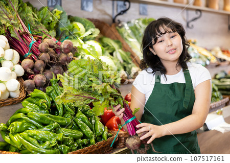 Hard-working girl supermarket employee puts fresh beets on the shelves of grocery department 107517161