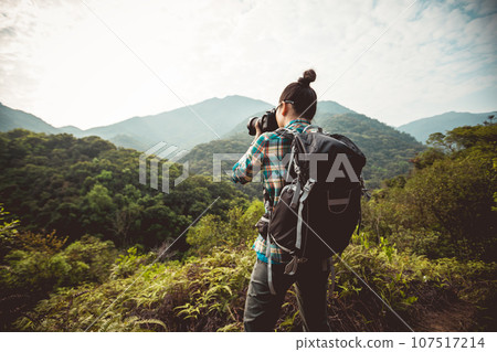 Woman photographer taking photo on morning mountain forest 107517214