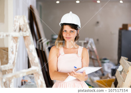 Portrait of positive woman construction manager with documents 107517554