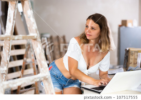 Young woman designer using laptop during repair works Young woman designer using laptop during repair works 107517555