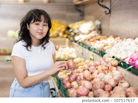 Young asian girl choosing onions on produce display i store 107517637