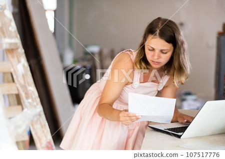 Woman construction manager checking project documentation, using laptop Woman construction manager checking project documentation, using laptop 107517776