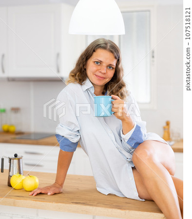 Portrait of a sexy dreaming girl with a mug of coffee in modern kitchen Portrait of a sexy dreaming girl with a mug of coffee in modern kitchen 107518121