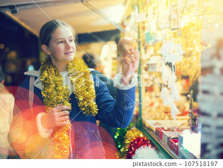 Happy teenage girl looking for New Year decorations in street market 107518197