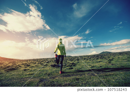 Woman trail runner cross country running at high altitude mountain peak 107518243