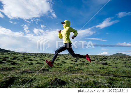 Woman trail runner cross country running at high altitude mountain peak 107518244