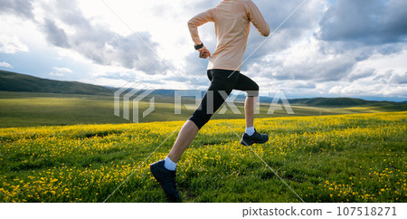 Woman trail runner cross country running at high altitude flowering mountain 107518271