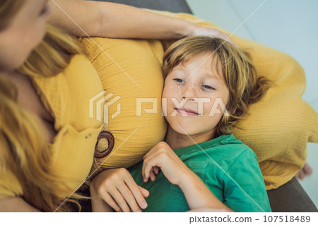 A heartwarming moment: pregnant mother and her older son sit on the sofa, engaging in a tender conversation about the upcoming pregnancy A heartwarming moment: pregnant mother and her older son sit on the sofa, engaging in a tender conversation about the upcoming pregnancy 107518489