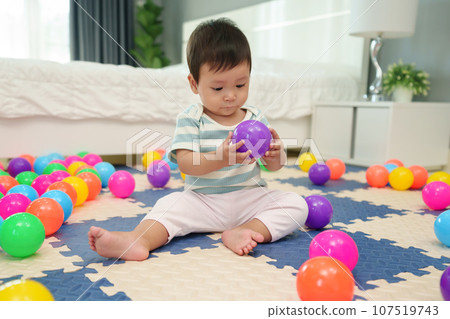 infant baby playing colorful plastic balls on jigsaw mat in bedroom infant baby playing colorful plastic balls on jigsaw mat in bedroom 107519743