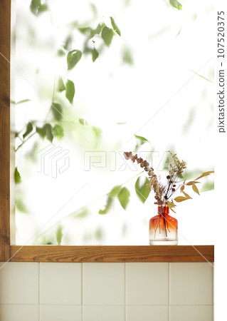 A comfortable room where warm afternoon sunlight comes in through a window with a view of tree leaves. A comfortable room where warm afternoon sunlight comes in through a window with a view of tree leaves. 107520375