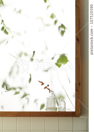 A comfortable room where warm afternoon sunlight comes in through a window with a view of tree leaves. 107520380