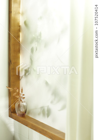 A comfortable room where warm afternoon sunlight comes in through a window with a view of tree leaves. 107520414