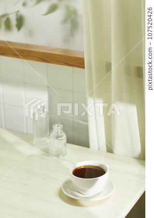 A comfortable room where warm afternoon sunlight comes in through a window with a view of tree leaves. 107520426