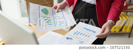 Woman sorts document papers with statistics and diagrams Woman sorts document papers with statistics and diagrams 107521330